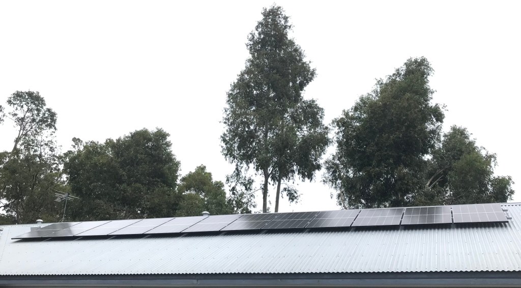 Rooftop solar panels with trees in the background.